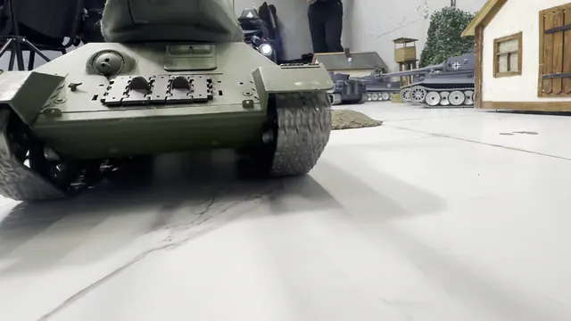 Physical 1:16 tank moving through a miniature arena between buildings and obstacles